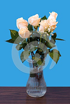 White roses with green leaves in a glass vase with water