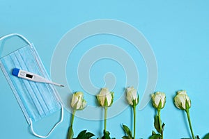 white roses  medical mask  thermometer thermometer  gifts in craft paper tied with a white satin ribbon on a bluebackground.