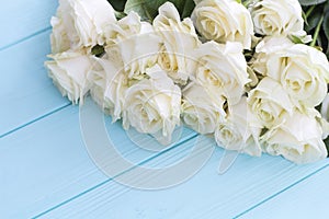 White roses on a turquoise wooden background.