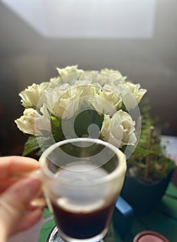 White roses in a vase and a cup of coffee on the table