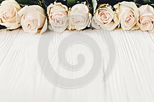 White roses on wooden background, copy space for text. Floral gr