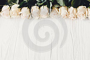 White roses on wooden background, flat lay with space for text.
