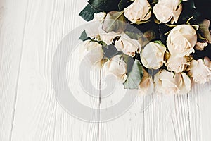White roses on wooden background, space for text. Floral greeting card mockup. Wedding invitation or happy mother day concept. Bo