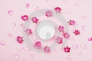 White round blank, pink rose flowers and petals for spa or wedding mockup on pastel background top view. Beautiful floral pattern.