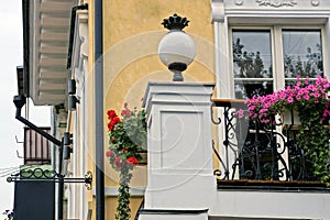 White round lantern on the wall by the balcony with flowerpots and a window