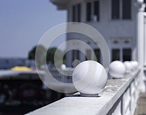 White round lanterns on a blurred natural background. A close-up of a spherical white glass plafond street lights.
