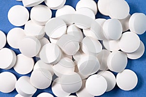 White round pharmaceutical pills on blue background