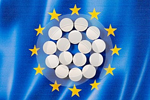 White round pharmaceutical pills on European Union flag background