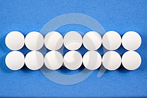 White round pharmaceutical pills on blue background