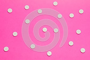 White round pharmacological tablets are on a pink polka dot background. Drug designation concept for women, gynecological drugs