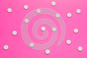 White round pharmacological tablets are on a pink polka dot background. Drug designation concept for women, gynecological drugs photo