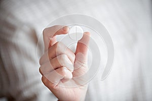 White round pill in womans hand