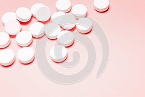 White, round pills on a pink background
