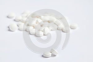 White round pills on a white background. A heap of small round meds.