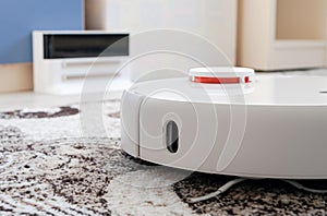 White round robotic vacuum cleaner on fitted carpet floor