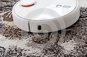 White round robotic vacuum cleaner on fitted carpet floor