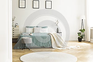 White round rug in front of green bed with blanket in bedroom in