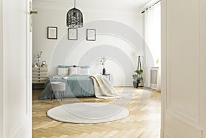 White round rug in spacious bedroom interior with green bed unde