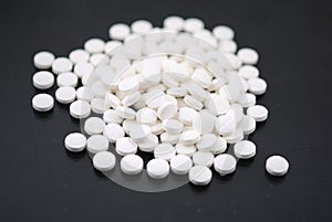 White round tablets closeup with sofl natural shadows and reflection on black background