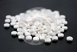 White round tablets closeup with sofl natural shadows and reflection on black background