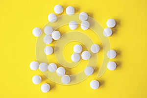 White round tablets on yellow background, top view