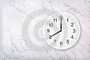 White round wall clock on marble background. Eight o`clock.