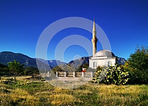 A white rural mosque on the background of mountains