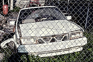 White rusted and scraped car wreck.