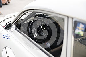 White SAab 96 on a parkinglot with the steeringwheel.