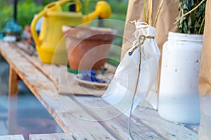 White sachet pouch tied around flower stems in a glass green house to dry for the next gardening season