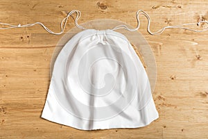 White sack bag on strings on wooden background, mock up photo
