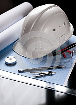 white safety helmet compasses compass paper sketches and goggles on engineer's desktop