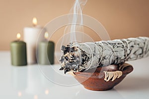 White sage and burning candles in background