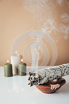 White sage and burning candles in background