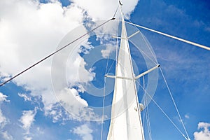 White sail on mast of boat over blue sky