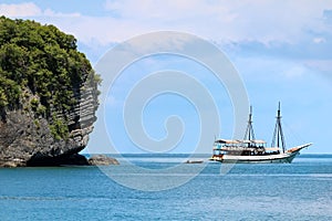 White sailboat in the ocean with views of the island and the blu