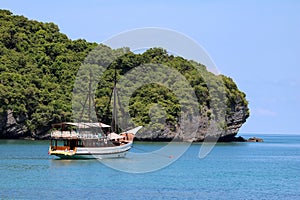 White sailboat in the ocean with views of the island and the blu