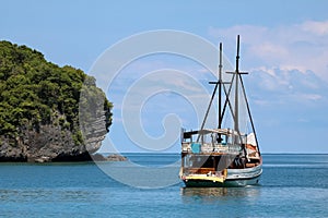 White sailboat in the ocean with views of the island and the blu