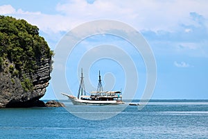 White sailboat in the ocean with views of the island and the blu