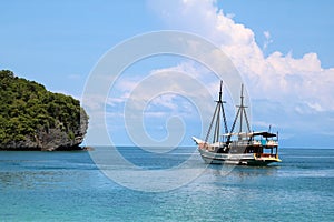 White sailboat in the ocean with views of the island and the blu