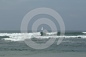 White sailboat in the ocean with waves