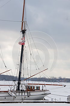 A white sailboat with two flags of Canada and the city of Toronto at a dock of Ontario lake, Toronto