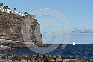 White sailboat under a cliff