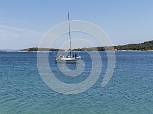 White sailing boat returning from the sea to the town port at the start of summer tourist season in Croatia