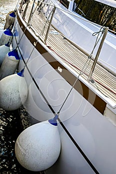 White sailing yacht moored in the port. Protective buoys hanging from the side of the ship. Close-up