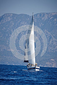 The white sails of yachts on the background of sea and mountains