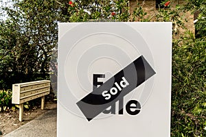 White for sale sign near the resedential appartment building with sold sticker on it. Real estate property investment boom concept