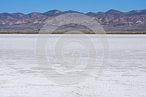 White salt flats of dry Soda Lake at Carrizo Plain National Monument with power line near lake shore. Temblor Range mountains on photo