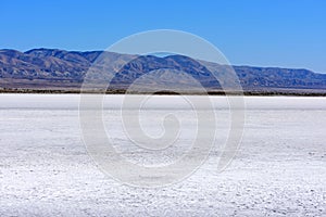 White salt flats of dry Soda Lake at Carrizo Plain National Monument. Temblor Range mountains on horizon on hot and sunny day photo