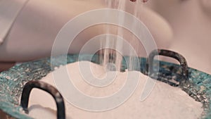 White salt is poured into a round bowl for spa treatments. Close-up